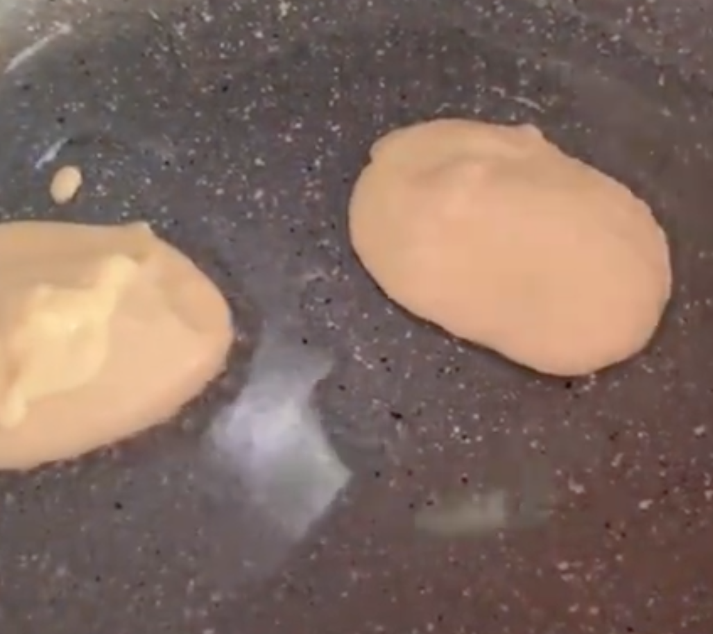 The process of frying pancakes in a frying pan.