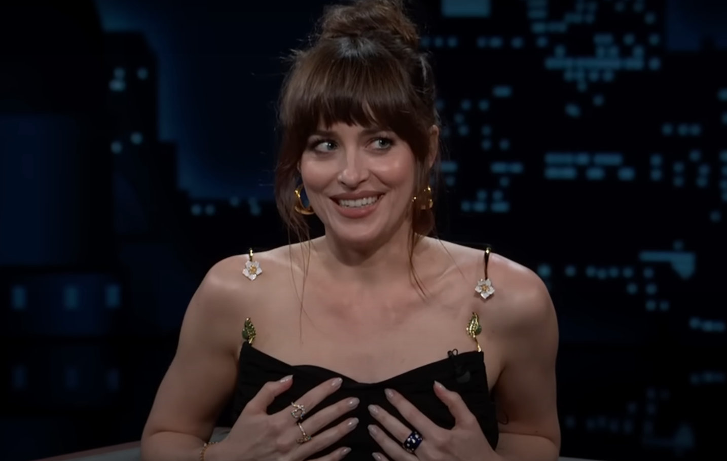 Dakota Johnson's dress almost fell down during an interview, but the Fifty Shades of Grey star quickly saved the situation. Video